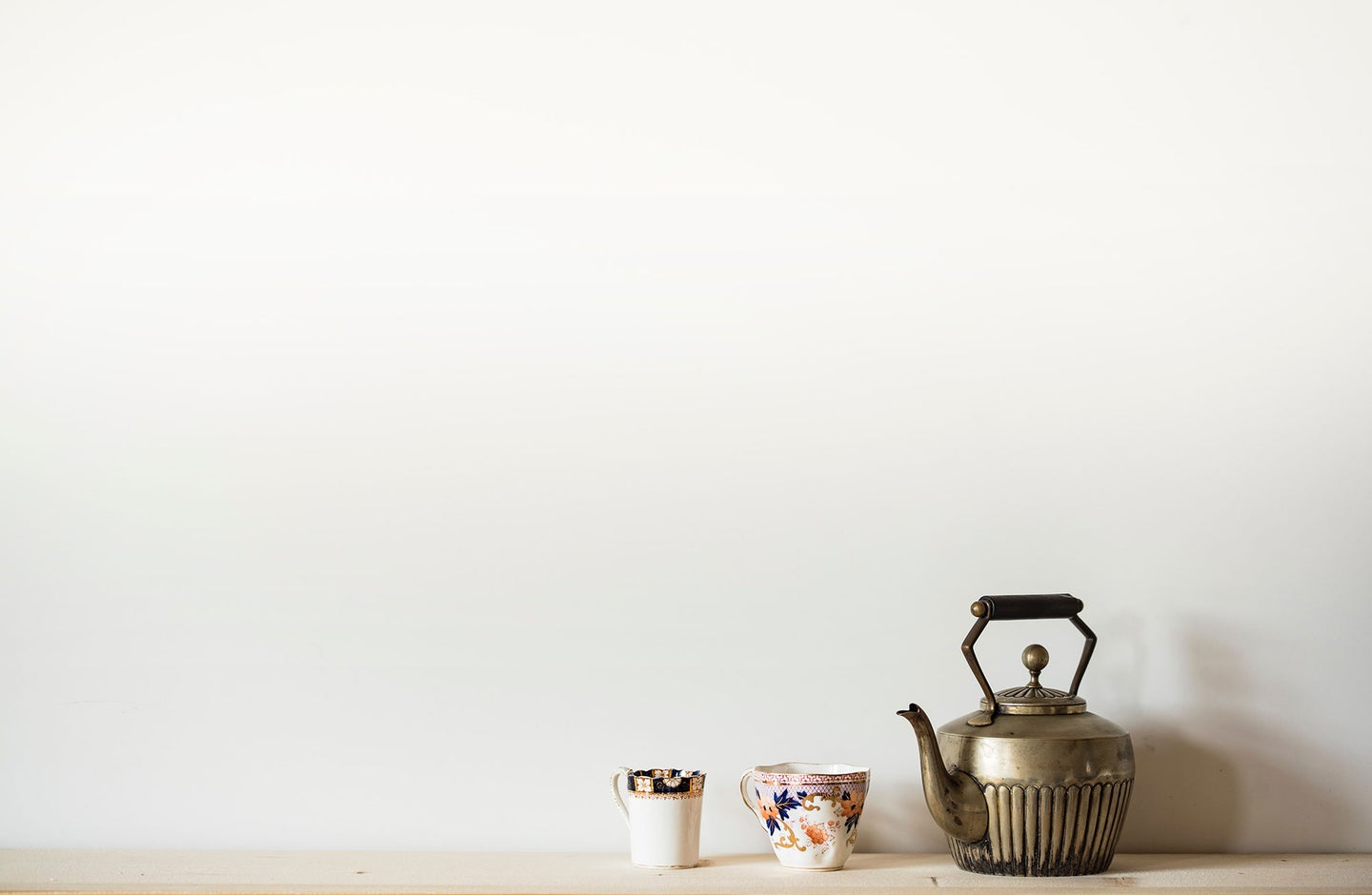 Brass teapot with patterned tea cups.